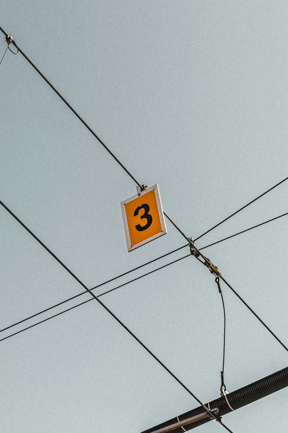 yellow 3 signboard hanging from cable