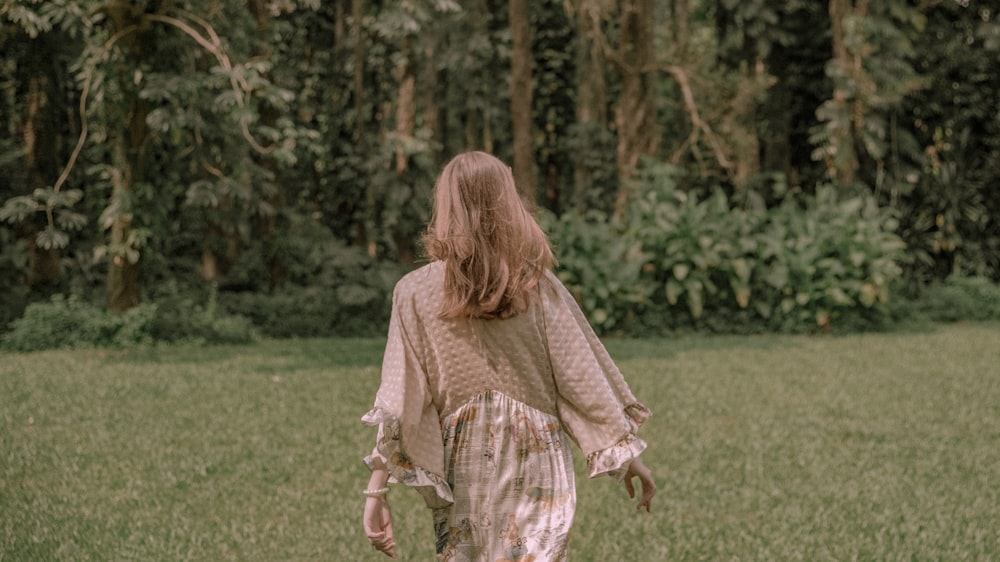 mulher usando vestido bege em pé na grama verde