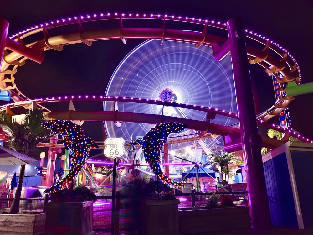 a ferris wheel at night with people walking around