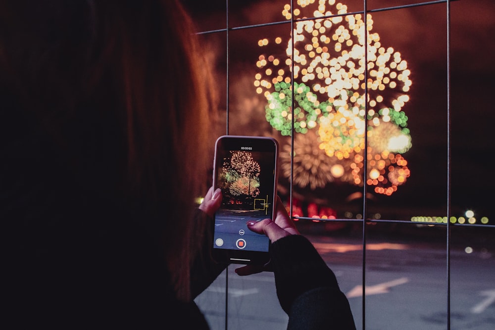 mulher tirando uma foto de fogos de artifício durante a noite