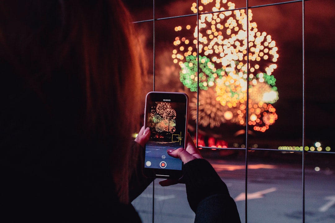 woman taking a picture of fireworks during night