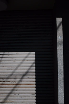 Technician adjusting the automatic mechanism of a steel shutter door with the azulportas logo visible.