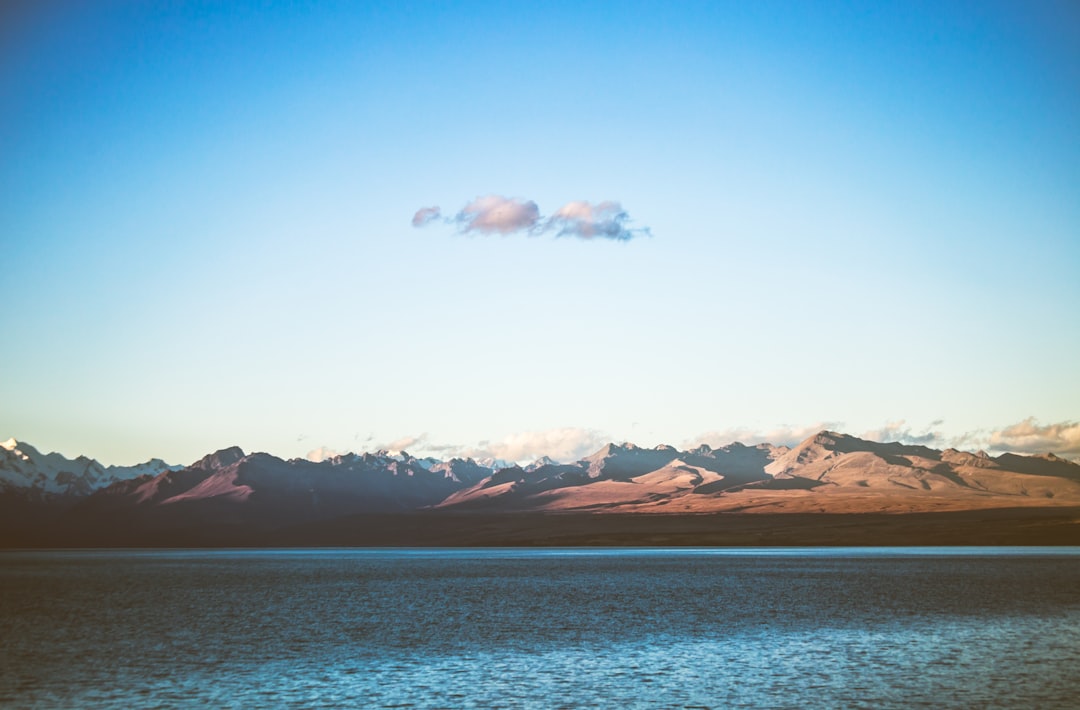 body of water near mountain at daytime