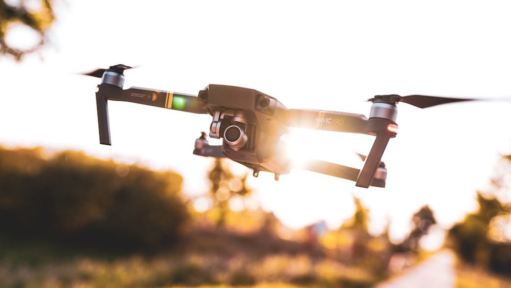 black drone flies under clear sky