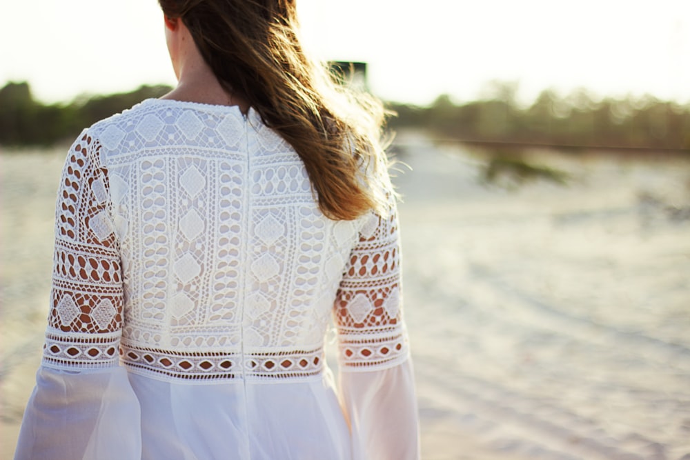 a woman in a white dress walking on a beach