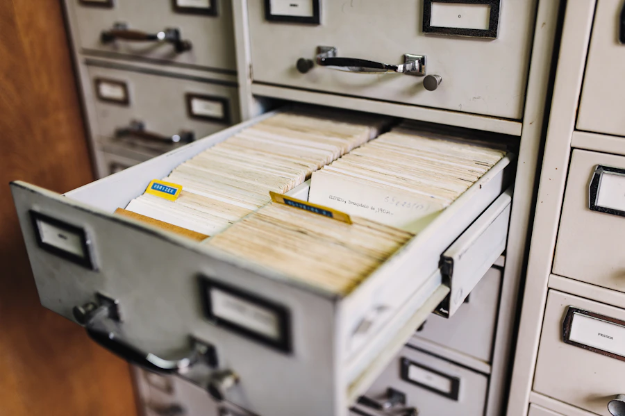 A grey filing cabinet drawer full of old paper files