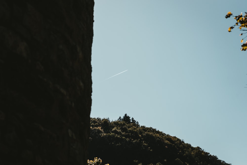 a view of a hill with a plane flying in the sky