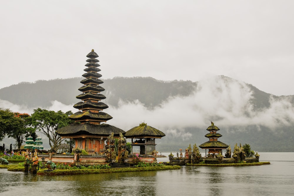 Templos de pagoda verde y roja junto a un cuerpo de agua bajo cielos blancos