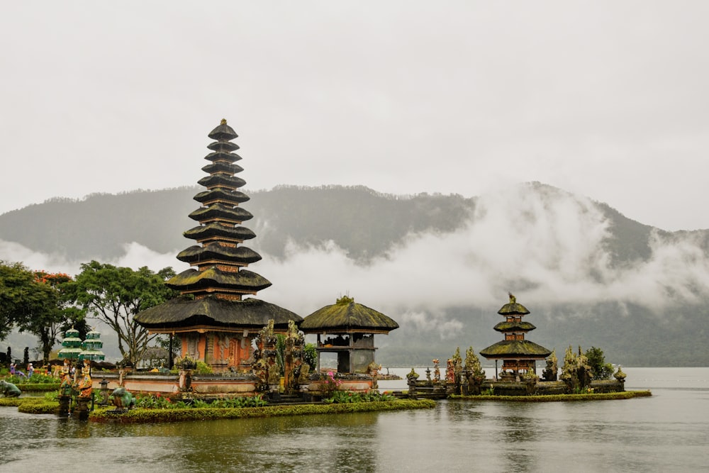green and red pagoda temples by body of water under white skies