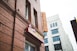 A red-brick building featuring signage for a barbecue restaurant with classic style signage and a neon sign that reads 'BARBECUE' vertically. Adjacent is a white building with multiple windows and an architectural design that contrasts with the rustic look of the brick.