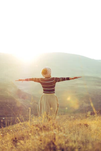 woman with wide open arms standing on grass