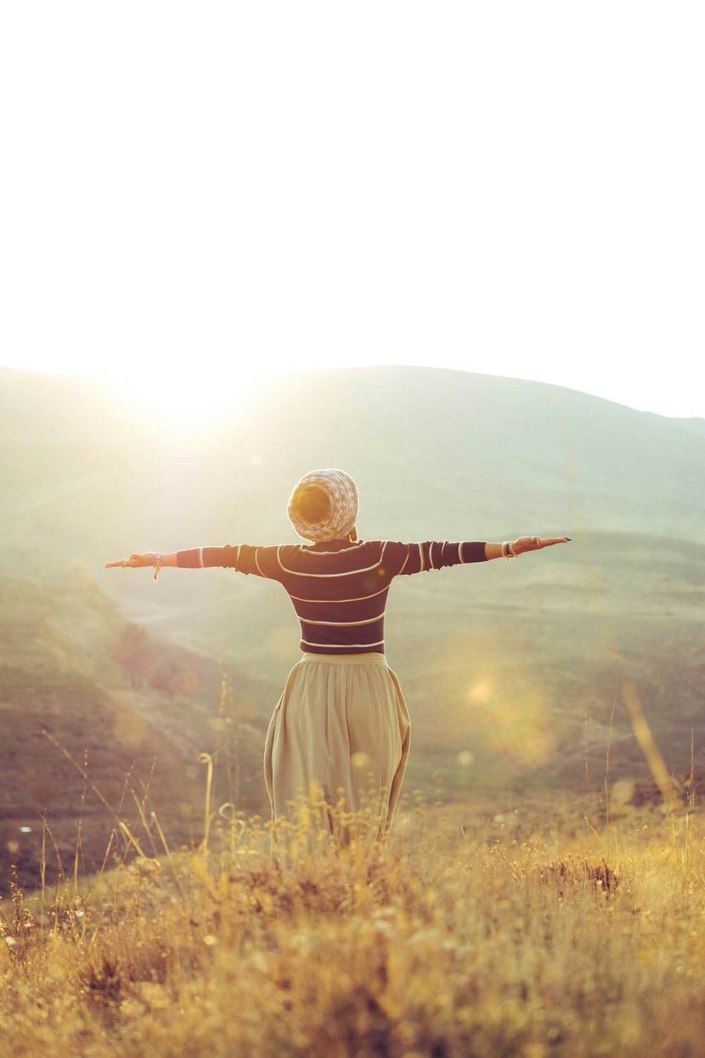 woman with wide open arms standing on grass