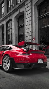 selective color photography of red Porsche sports car parked at roadside