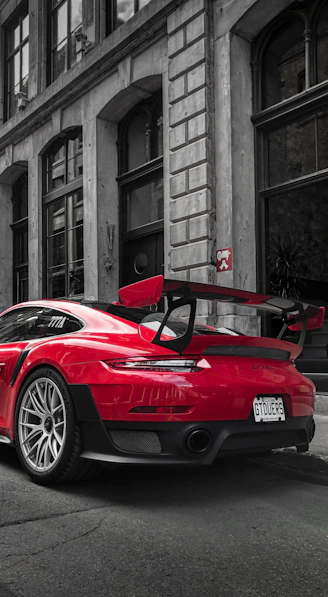 selective color photography of red Porsche sports car parked at roadside