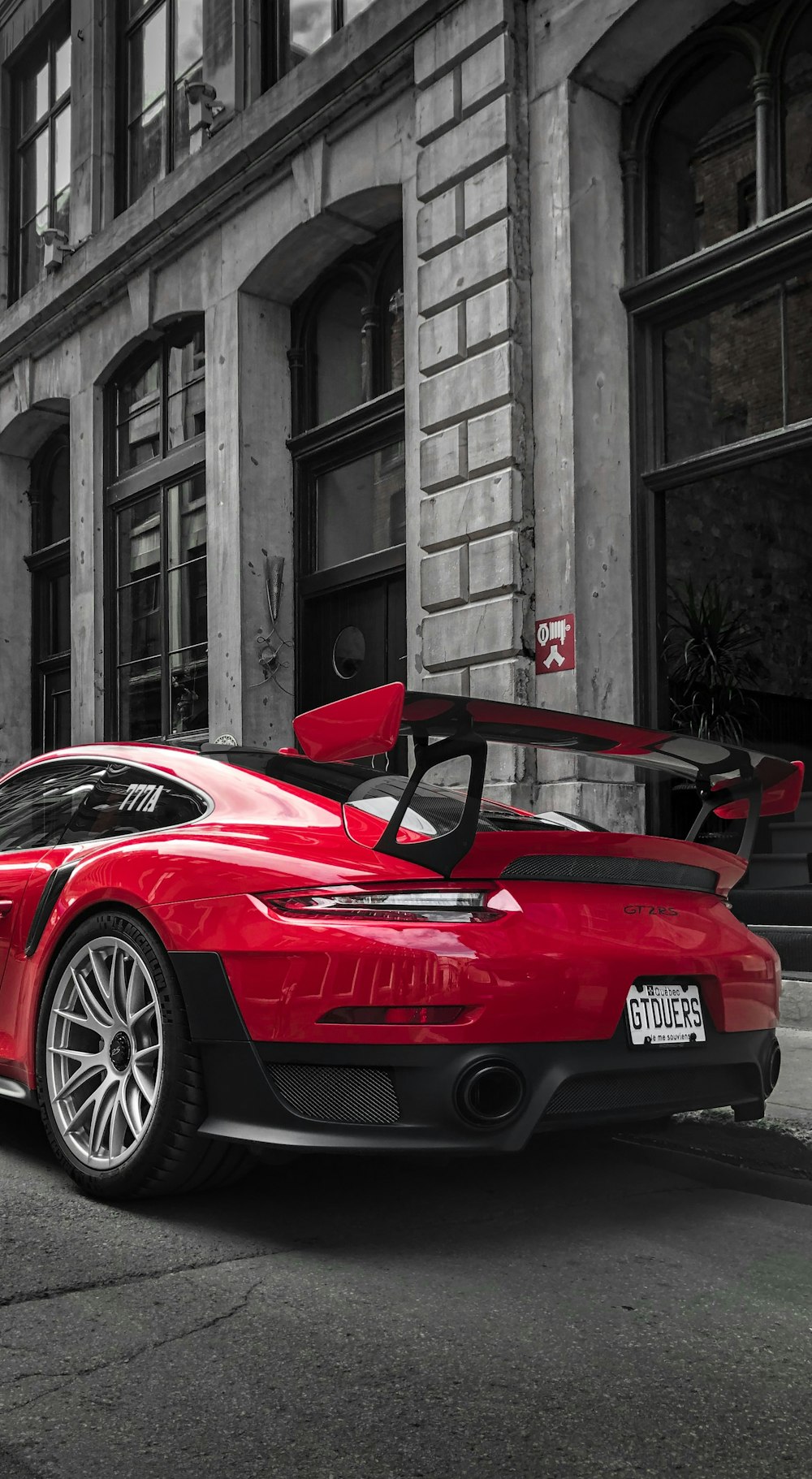 selective color photography of red Porsche sports car parked at roadside