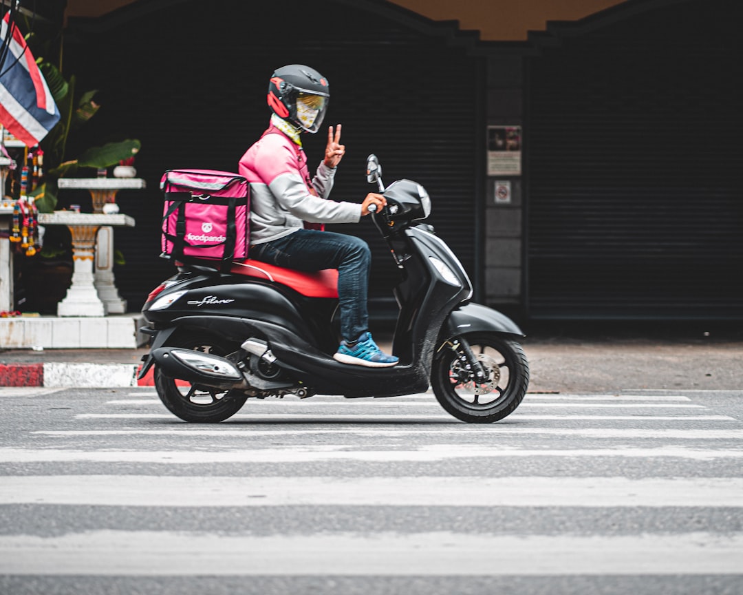 man wearing white and pink jacket sitting on motor scooter