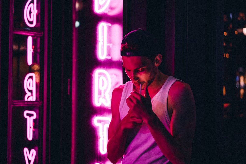 smoking man standing near neon signage