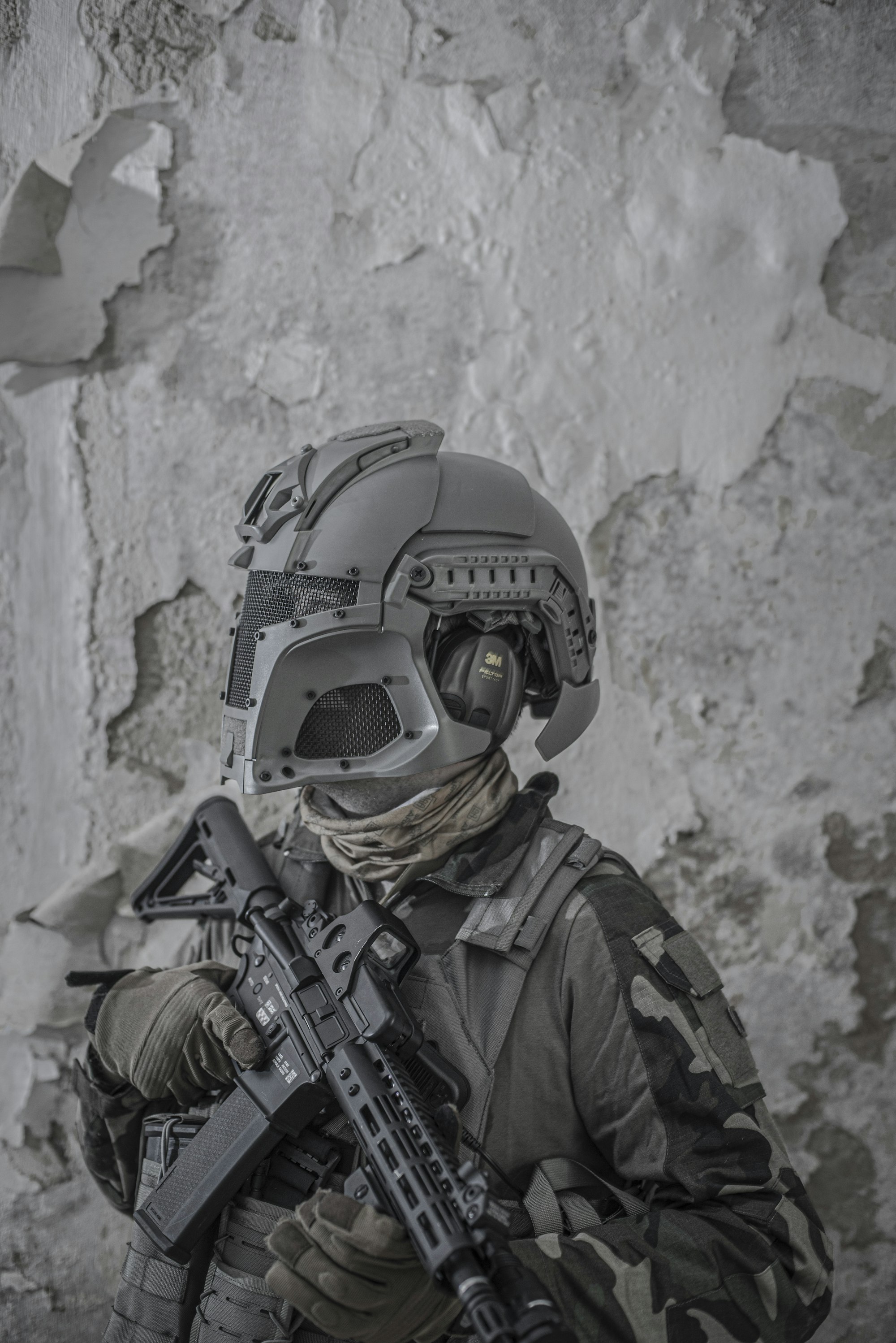 Airsoft player in protective mask and helmet, with the airsoftgun