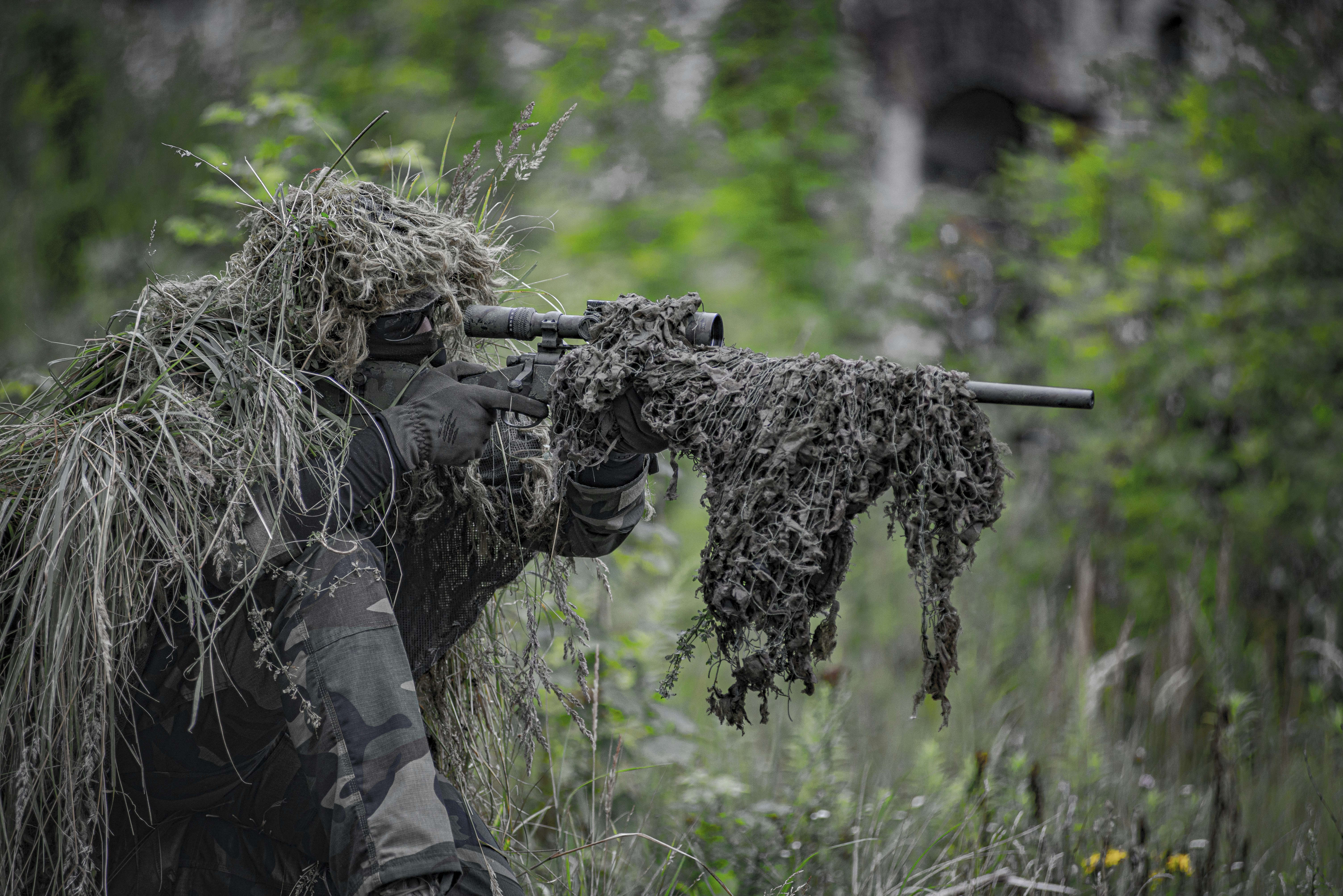 Airsoft sniper, waiting and aiming, player in camouflage
