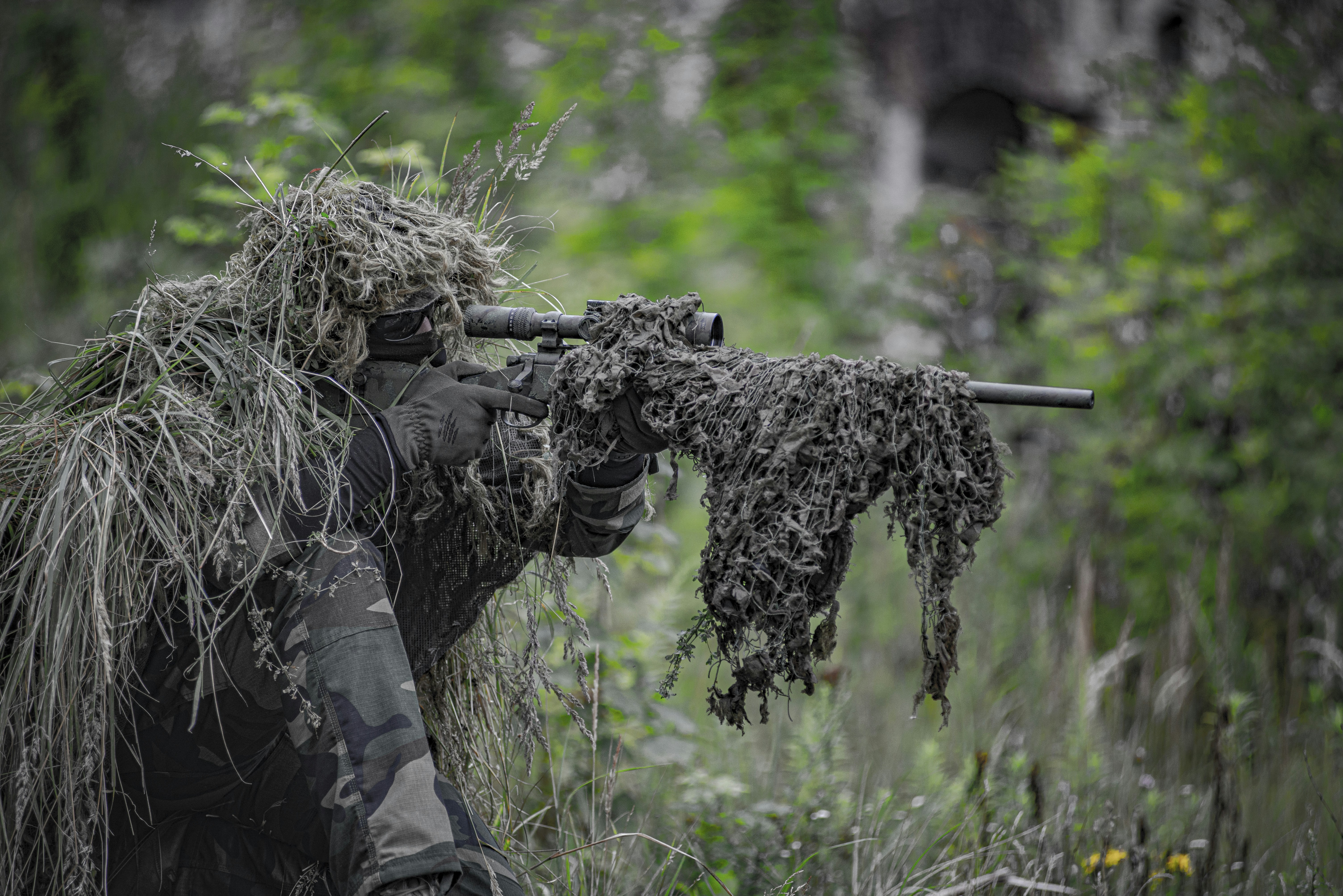 Airsoft sniper, waiting and aiming, player in camouflage