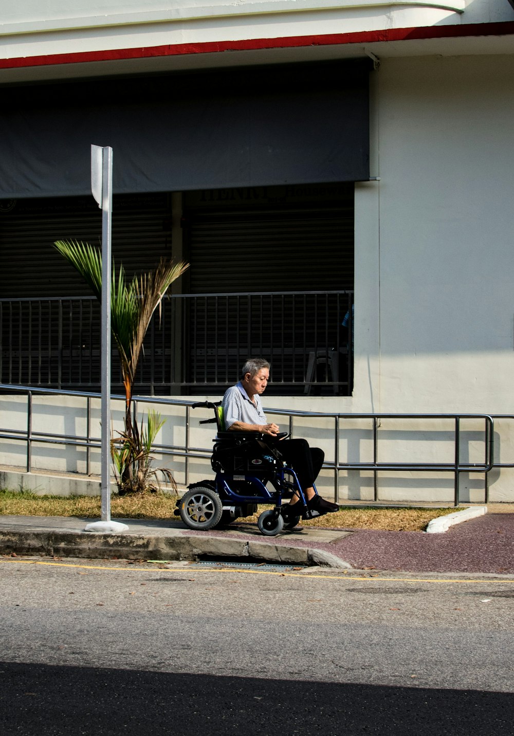 man riding wheelchair at roadside during daytime
