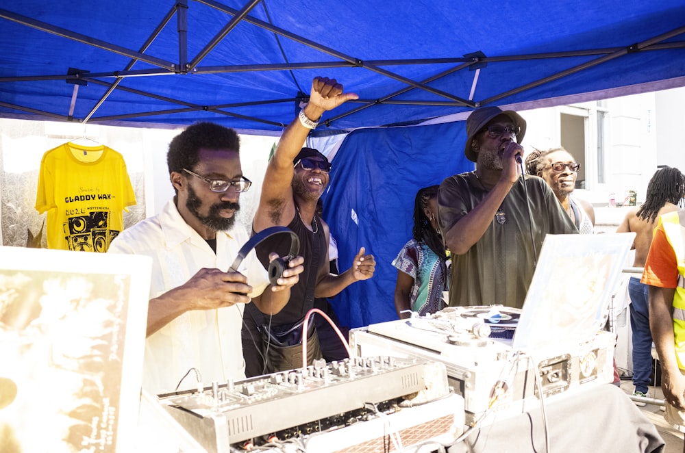 três homens atrás da mesa sob a tenda do dossel azul