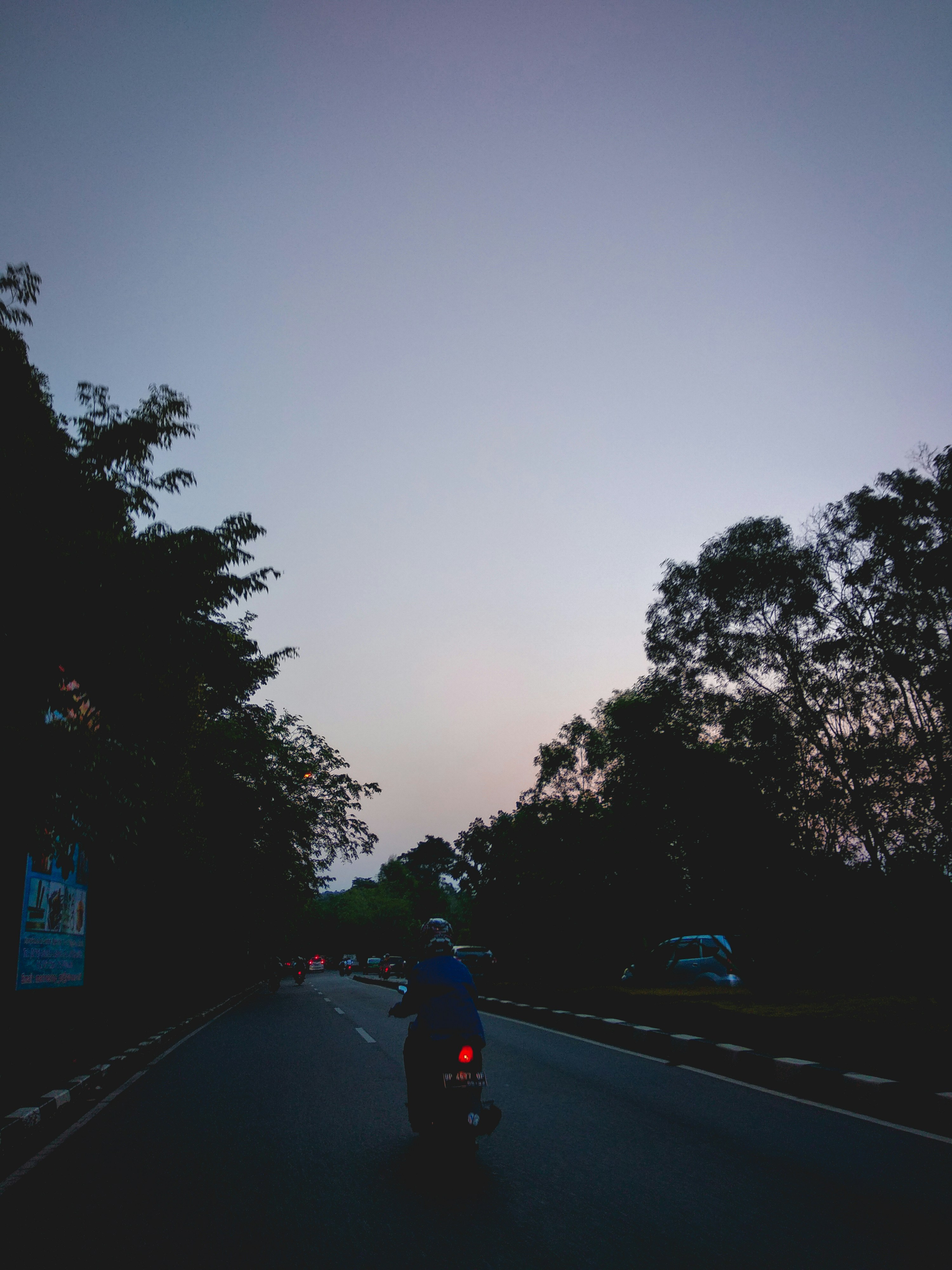 Motorcycle group riding through mountain pass at dusk, headlights visible, dramatic dark sky, deep shadows, cinematic wide shot