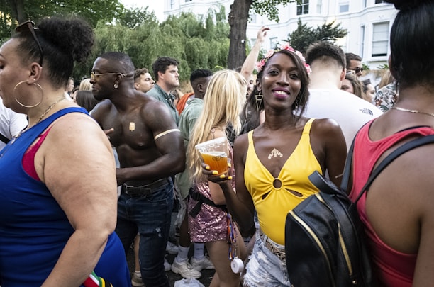 Close-up of a smiling woman holding a drink, surrounded by lively event attendees.