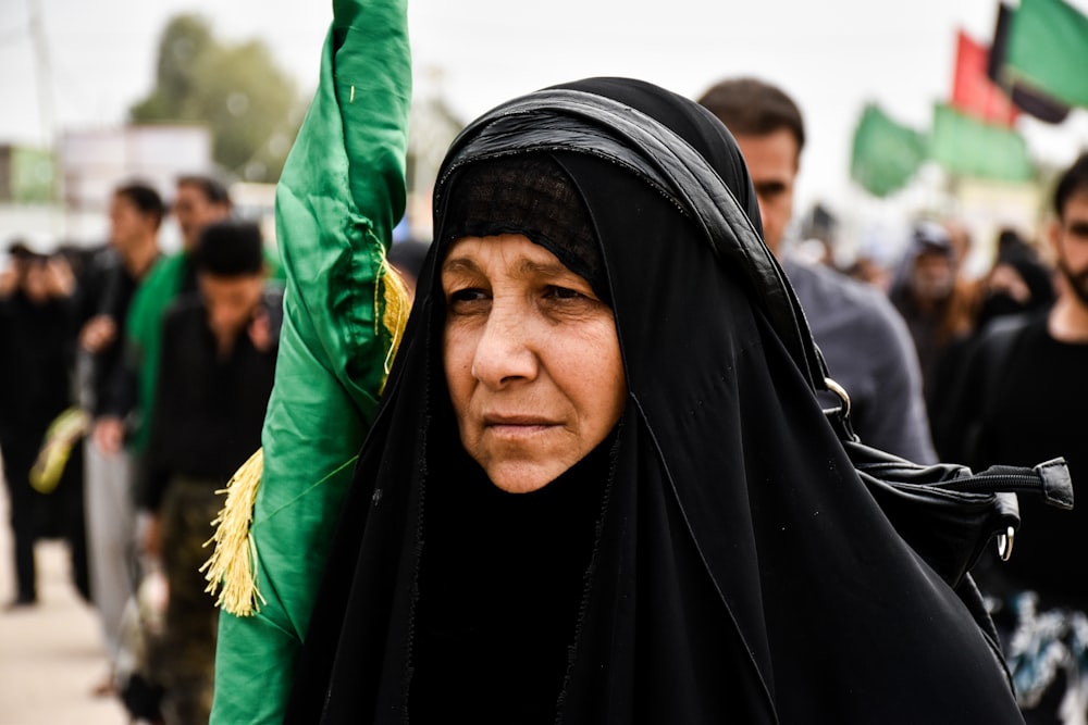 woman in black hijab holding folded flag during daytime