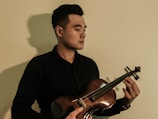 A serene portrait of the musician holding a violin against a black background.