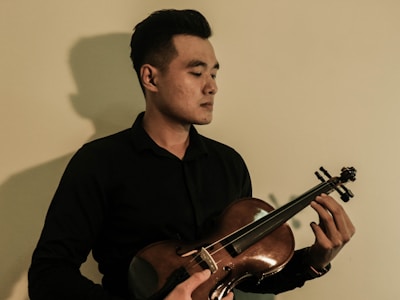 A serene portrait of the musician holding a violin against a black background.
