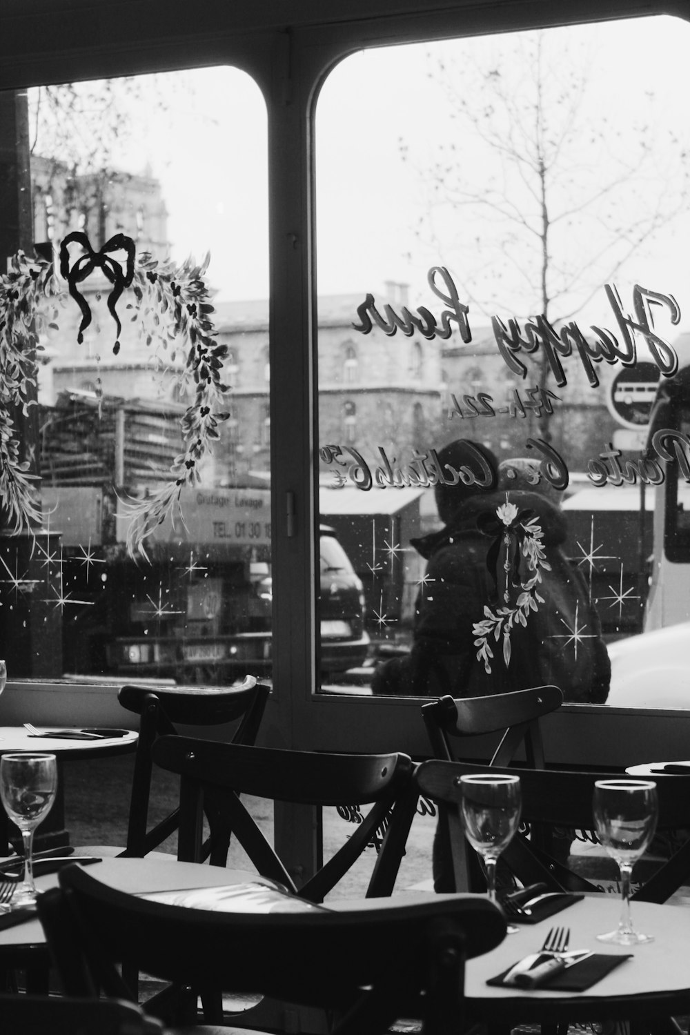 grayscale photography of empty table and chairs beside glass wall