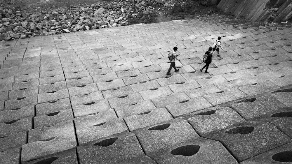 fotografia em tons de cinza de três pessoas caminhando