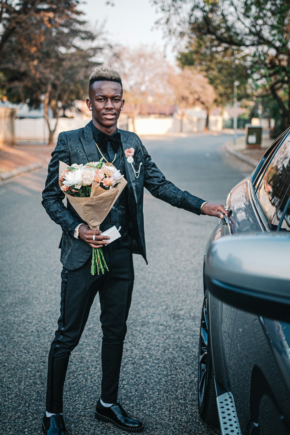 man holding bouquet of flower standing beside car