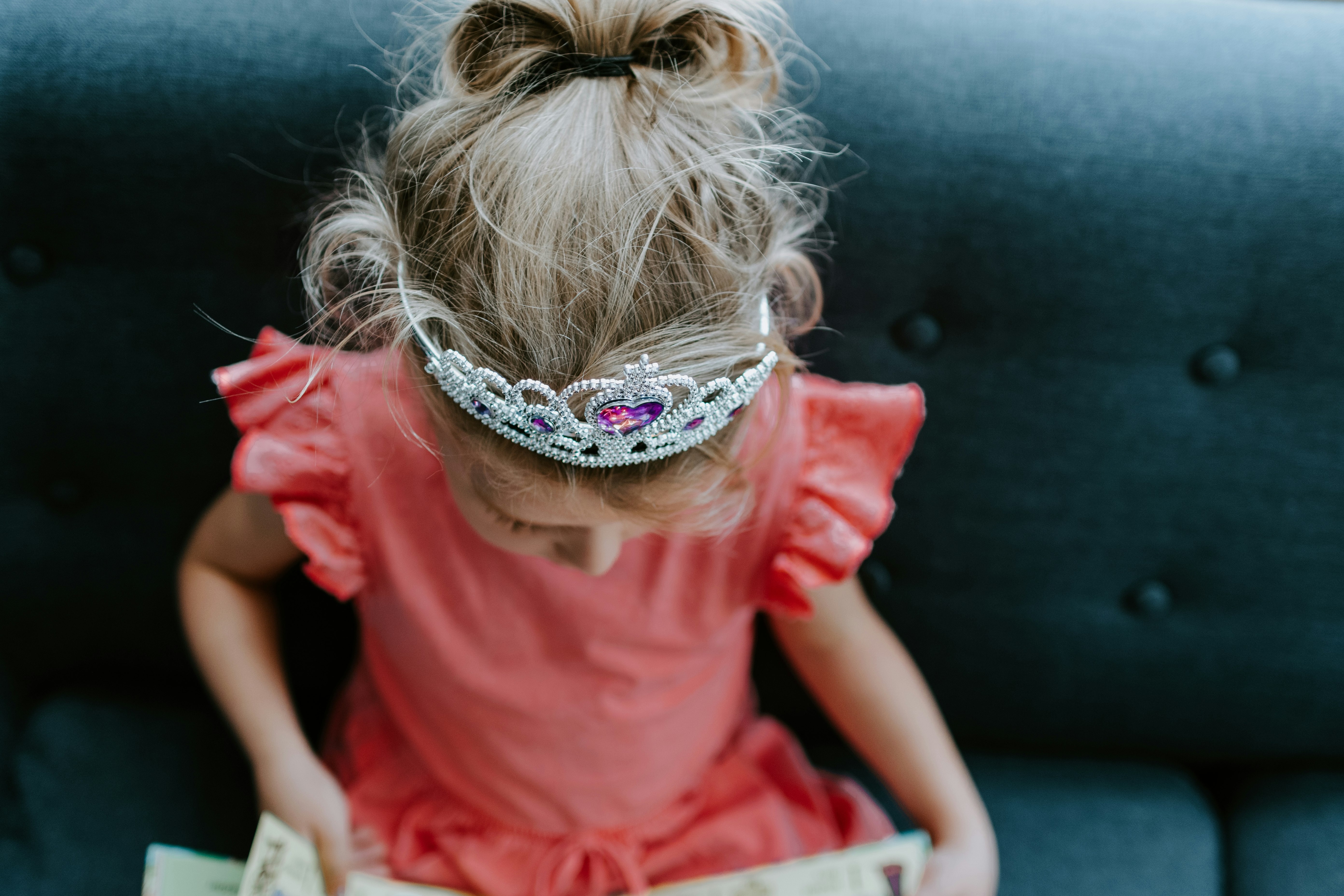 Little girl in a princess tiara reading a book