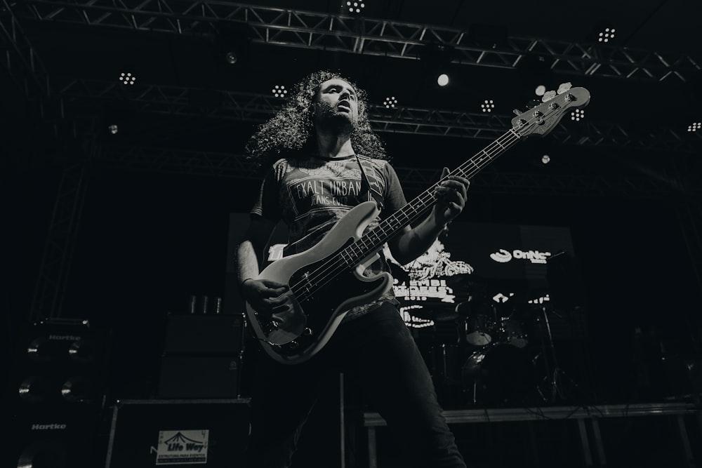 grayscale photography of man holding guitar