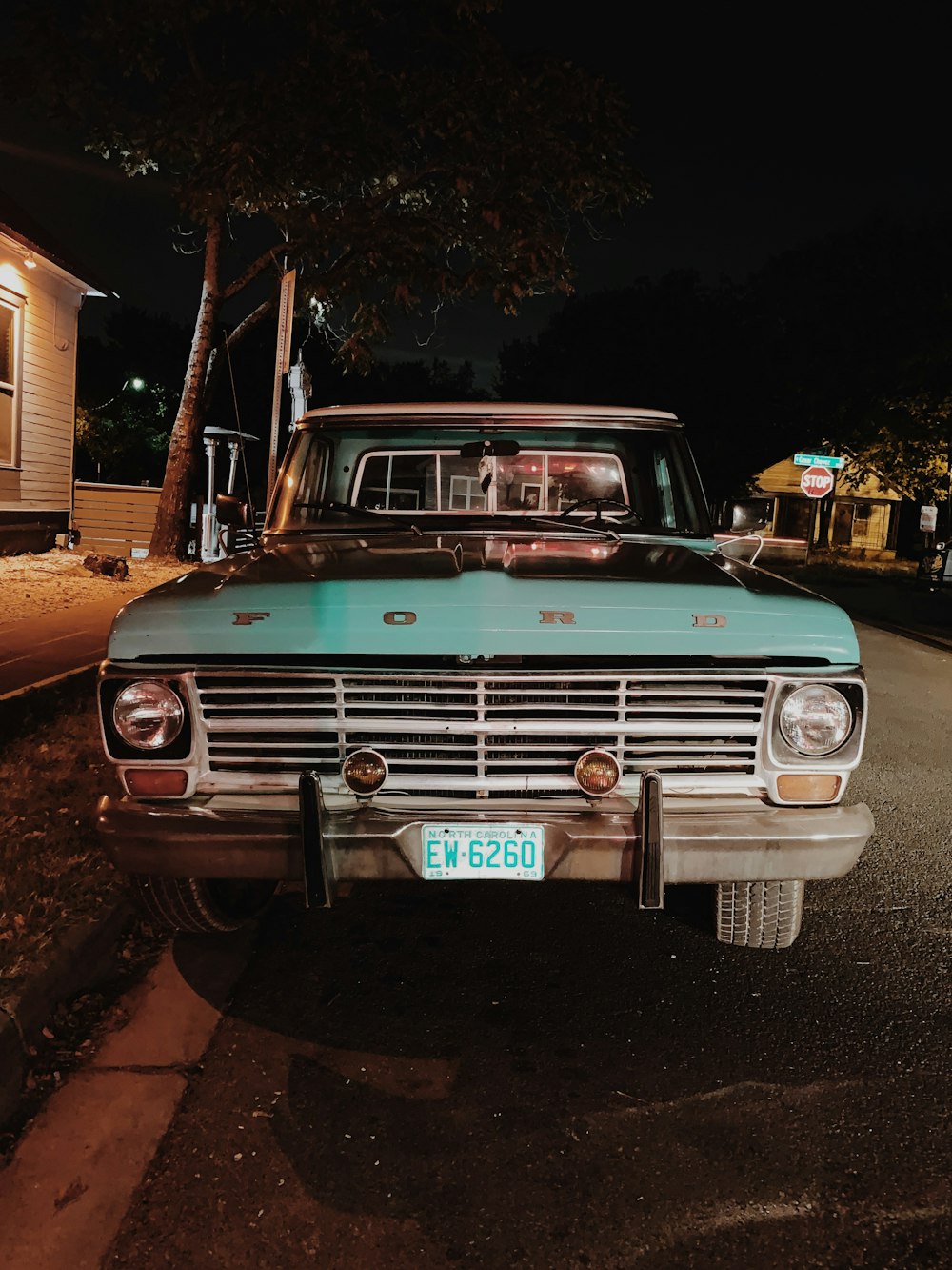 teal Ford car parked outside white house at night