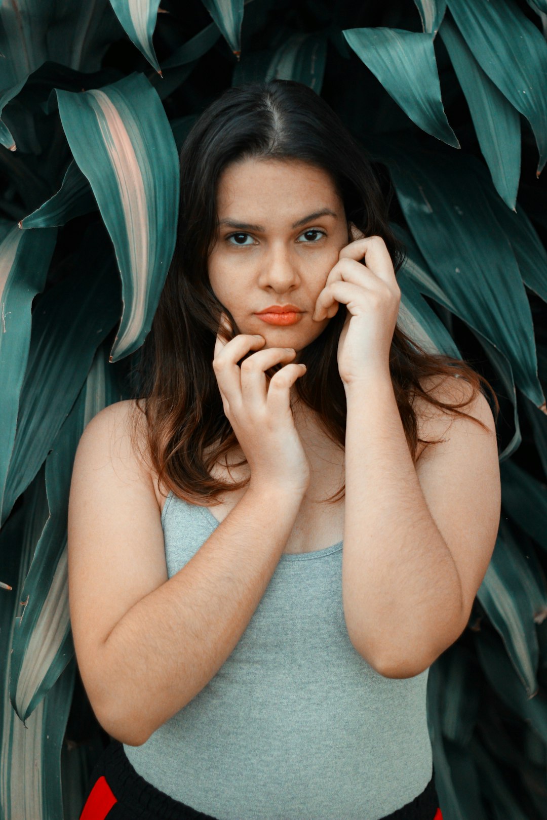 woman wearing grey camisole top beside green-leafed plant