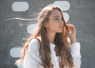 woman in white top and blue denim bottoms standing outdoors