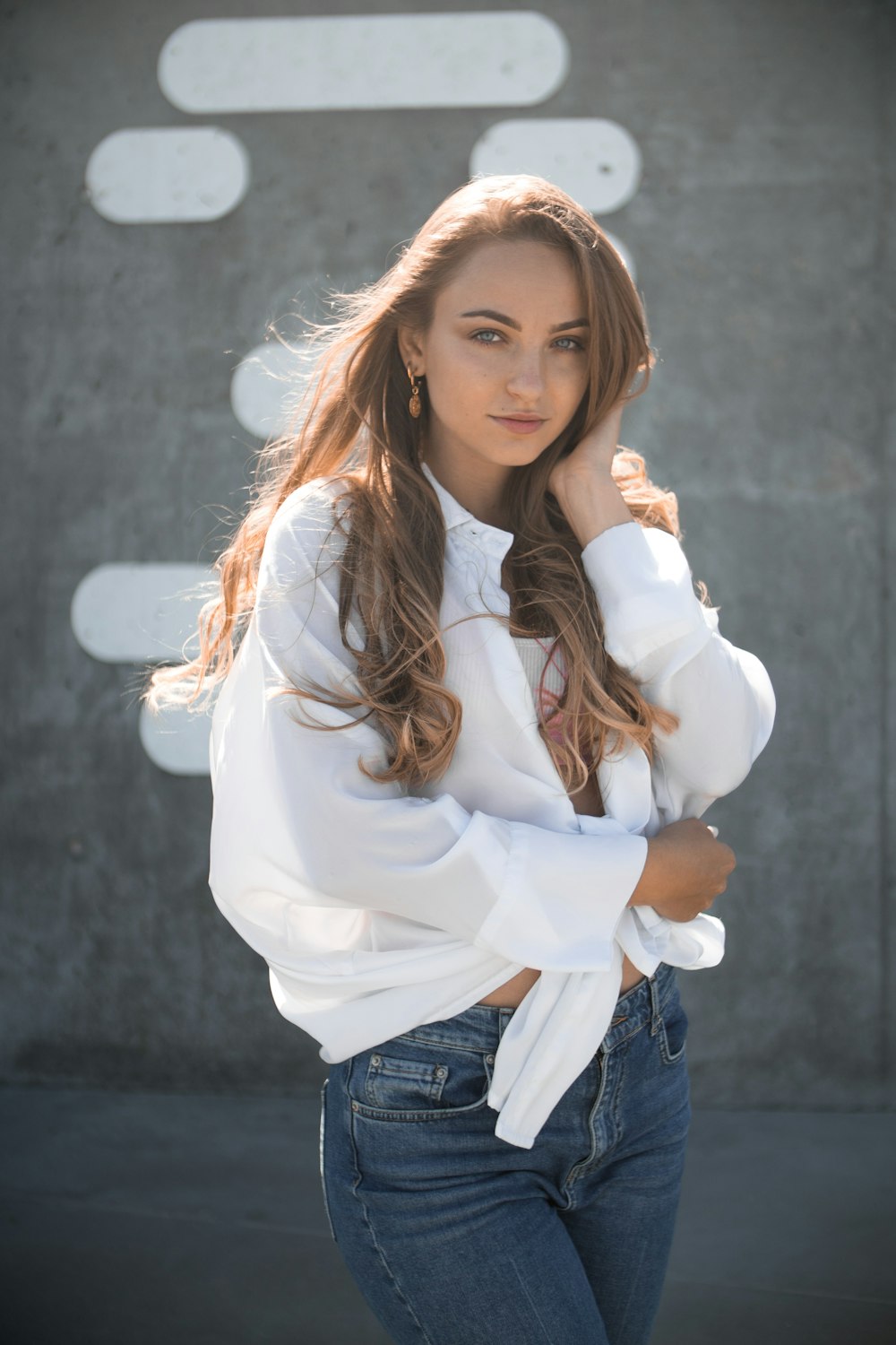 woman wearing white long-sleeved shirt and blue denim fitted jeans