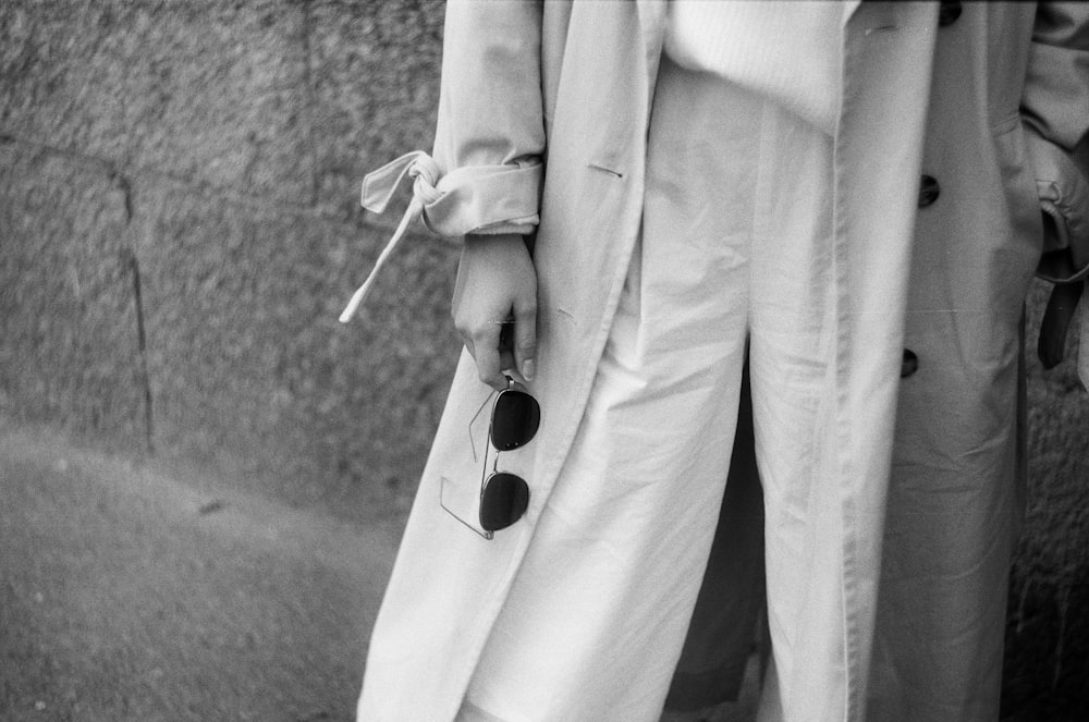 grayscale photography of person holding sunglasses