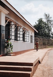 A Prime Force Security officer in uniform walking along a commercial building perimeter at dusk.