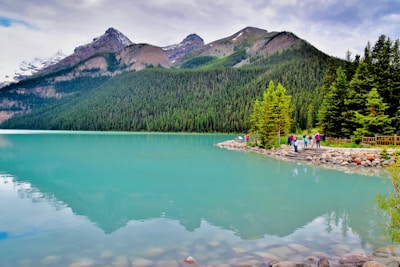 A group of trekkers resting beside a crystal-clear lake near Senaru, surrounded by lush green forest.