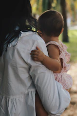 woman carrying a baby girl facing to the back