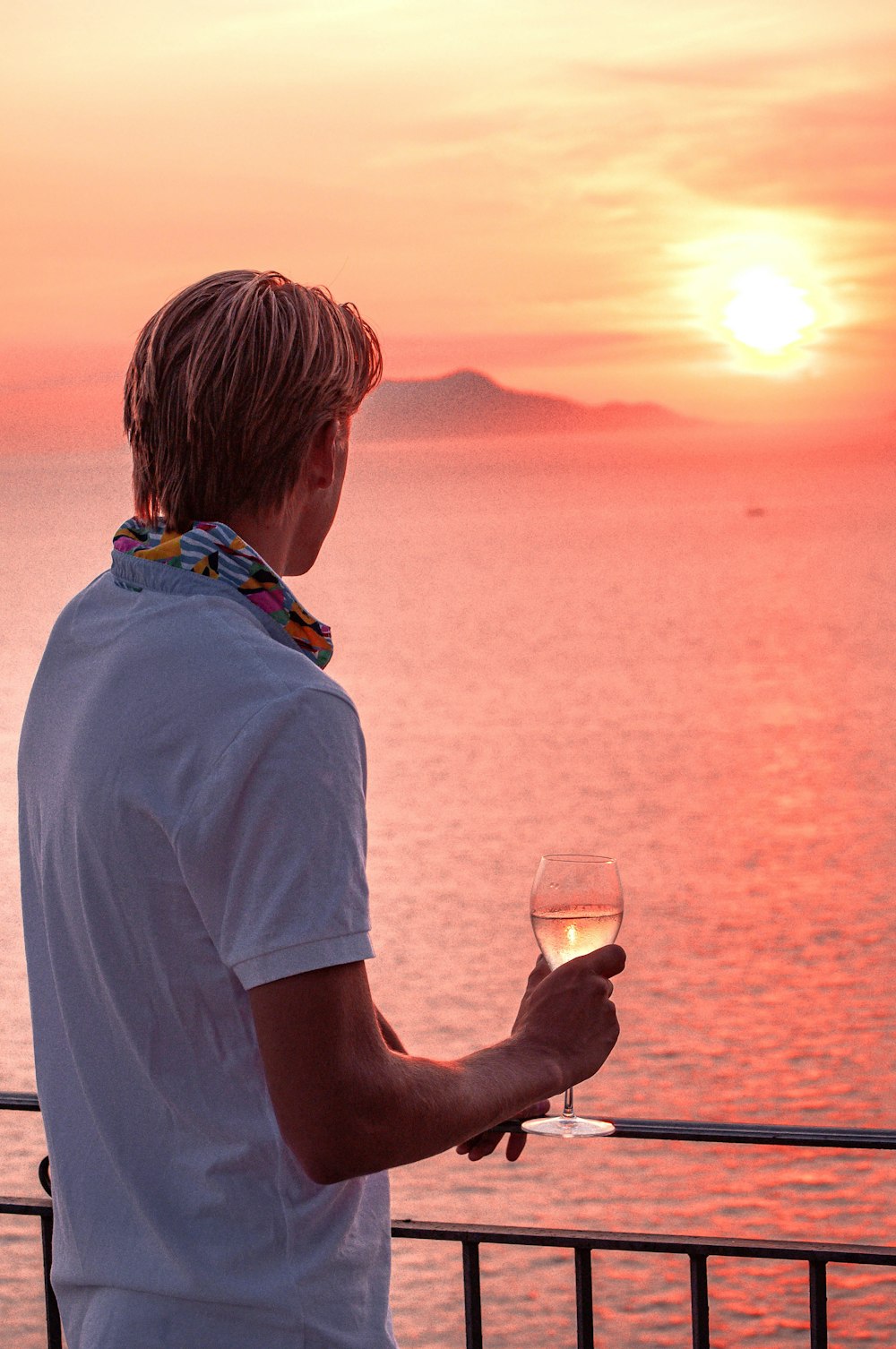 man in white t-shirt holding filled wine glass