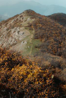 A scenic trail winding through the Serra da Lousã with vibrant autumn leaves and distant mountain views.