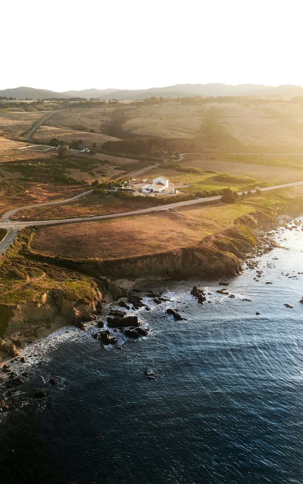 aerial photography of green field and body of water during daytime