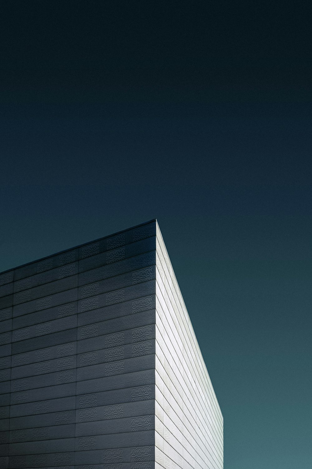 fotografia dal basso di un edificio in cemento bianco sotto un cielo blu