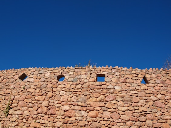 A sturdy gabion wall blending harmoniously with a rocky Patagonian mountain landscape under a clear blue sky.