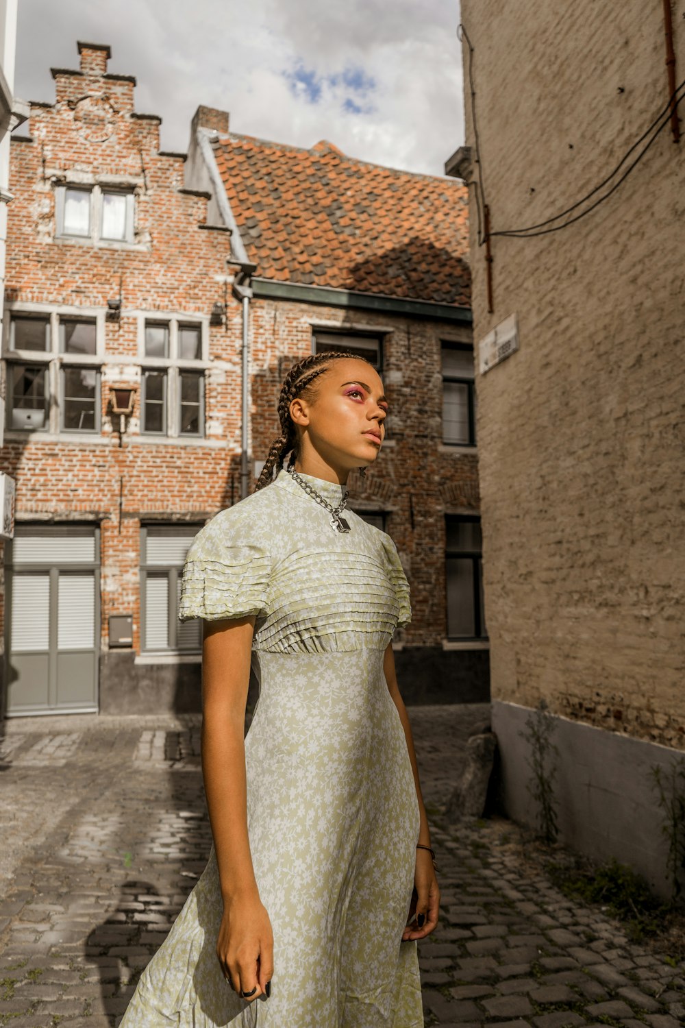 woman wearing gray short-sleeved dress standing near brown buildings